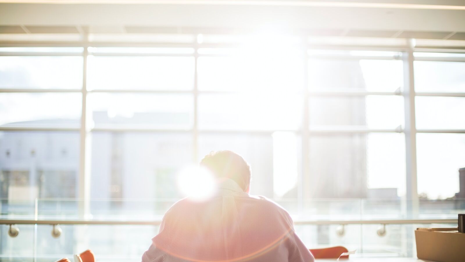 man sitting on chair in front on window during daytime