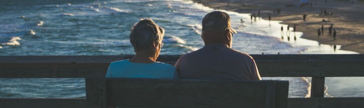 man and woman sitting on bench in front of beach