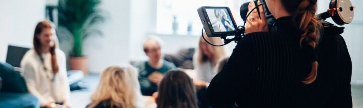 woman holding camera standing near people