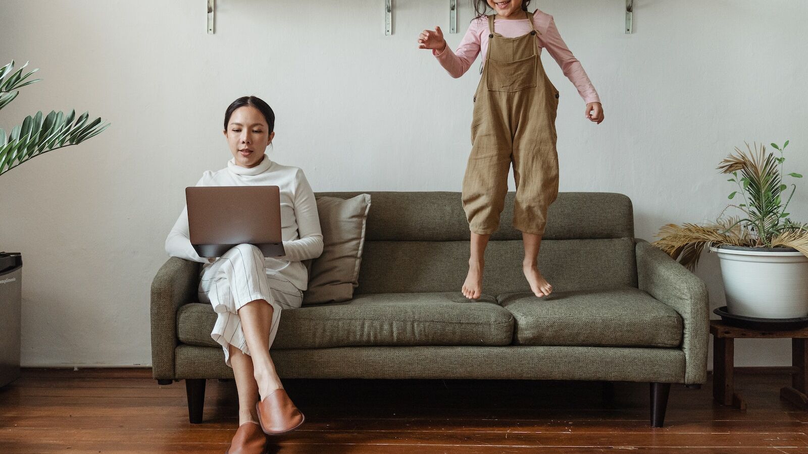 Focused mother working on laptop near disturbing daughter