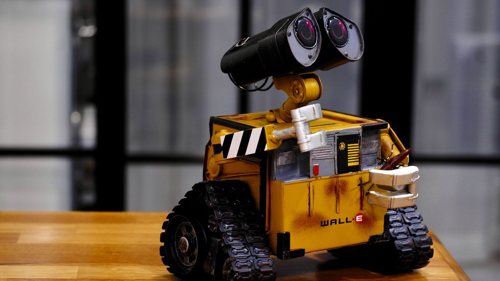 yellow and black Wall-E toy on brown wooden table