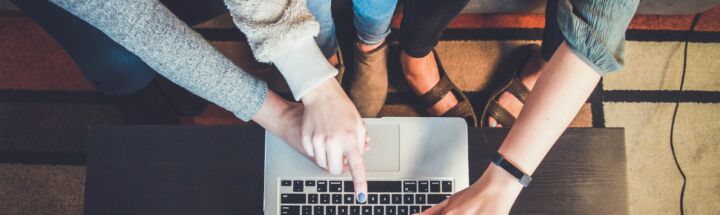 three person pointing the silver laptop computer