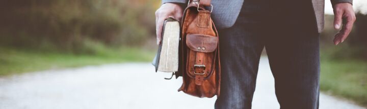 man holding book on road during daytime