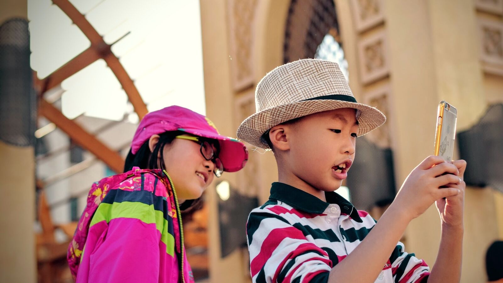 girl watching behind boy holding smartphone