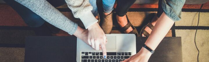 three person pointing the silver laptop computer