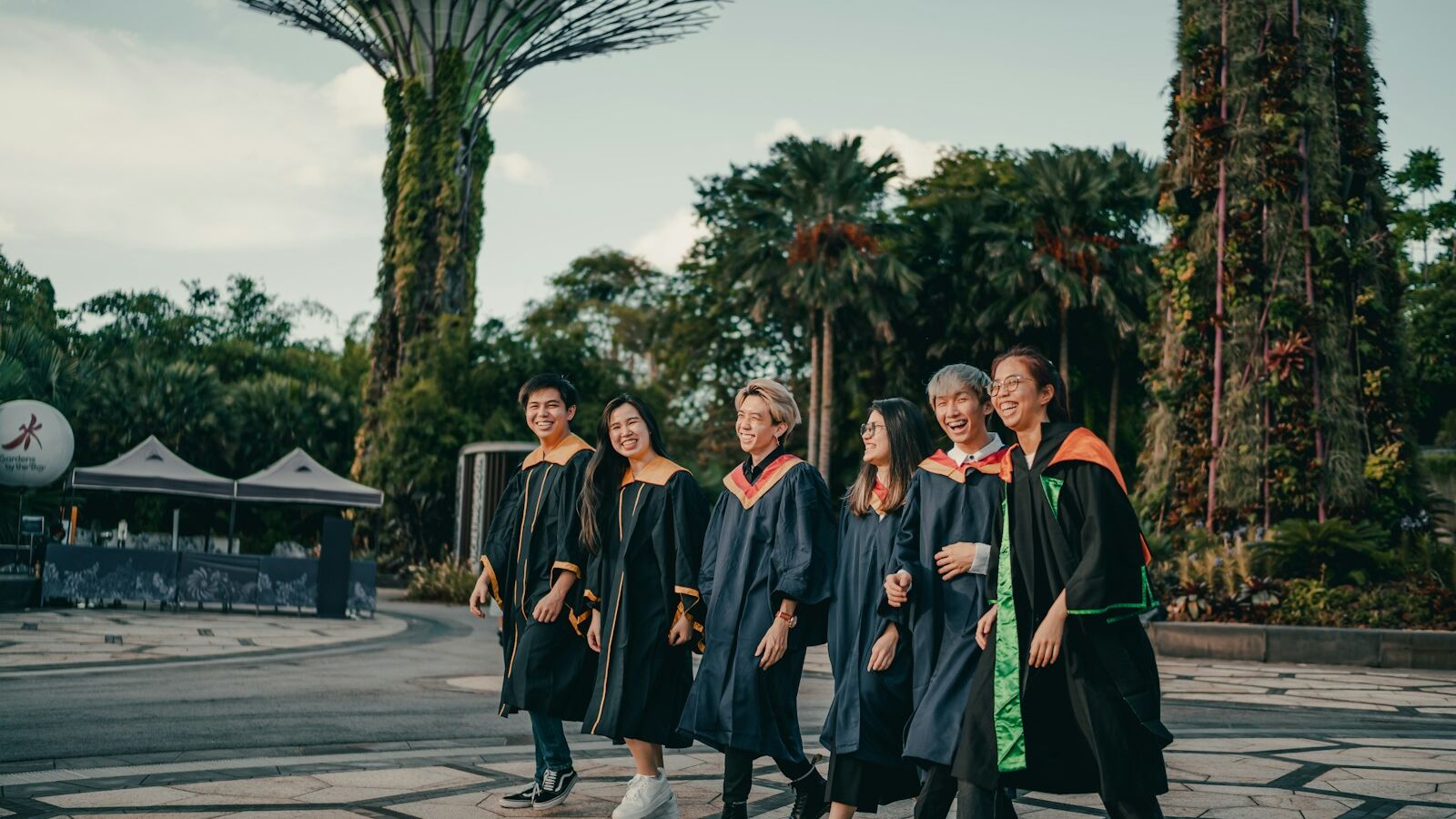 group of people in black academic dress standing on gray concrete pavement during daytime