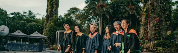 group of people in black academic dress standing on gray concrete pavement during daytime