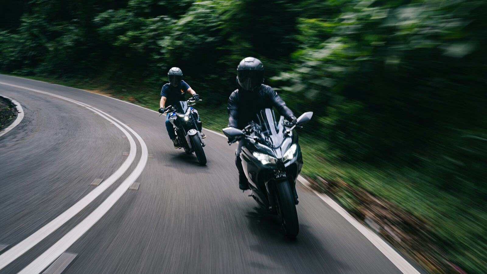 two people riding motorcycles down a curvy road
