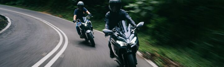 two people riding motorcycles down a curvy road