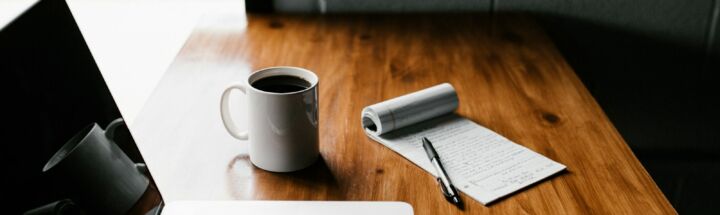 MacBook Pro, white ceramic mug,and black smartphone on table