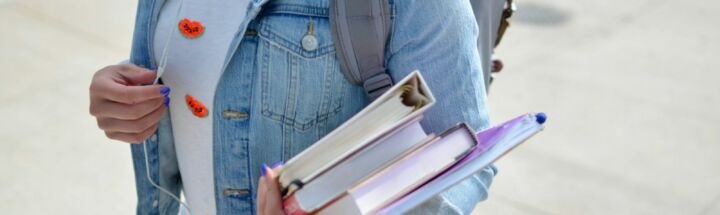 woman wearing blue denim jacket holding book