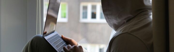 a person sitting on a window sill using a laptop