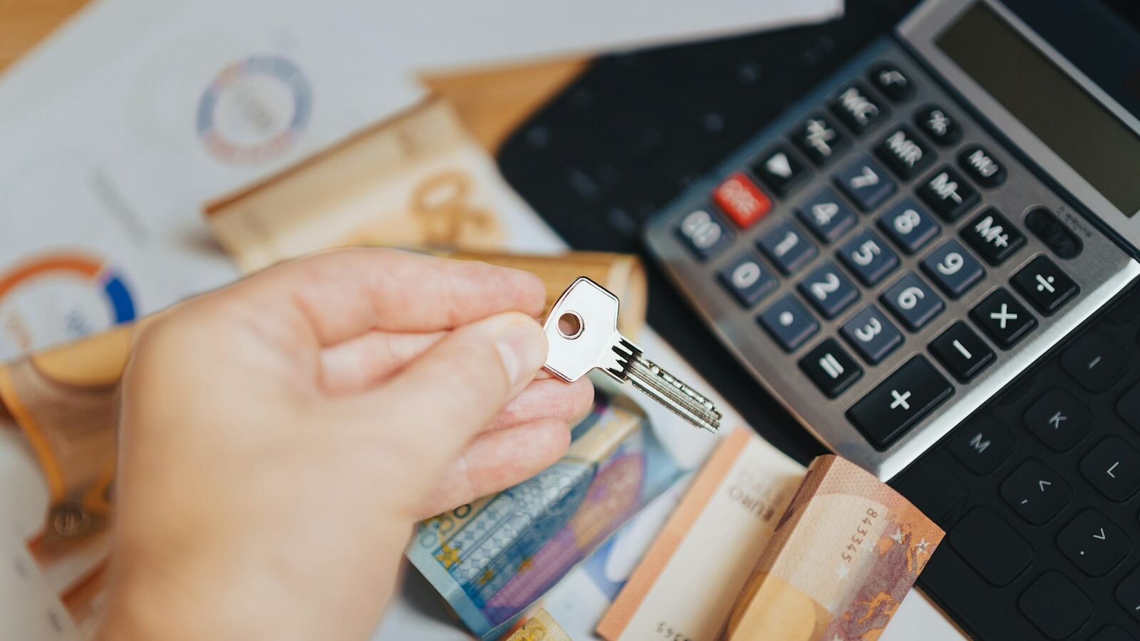 A person is putting money in front of a calculator