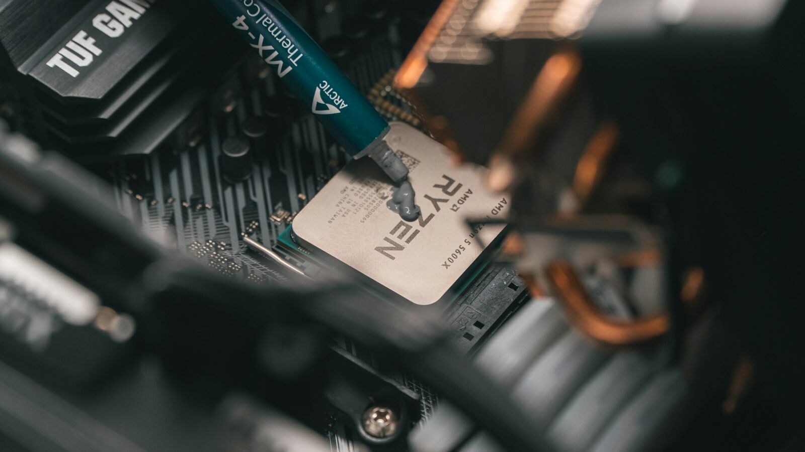 a close up of a person holding a pen near a computer motherboard
