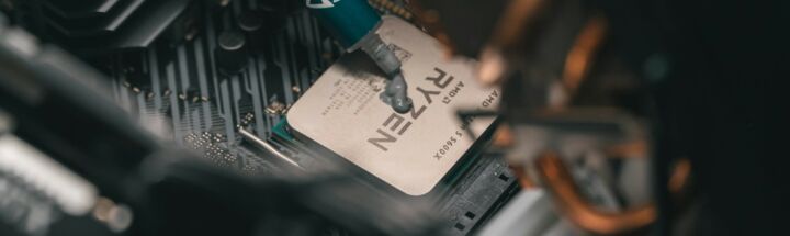 a close up of a person holding a pen near a computer motherboard
