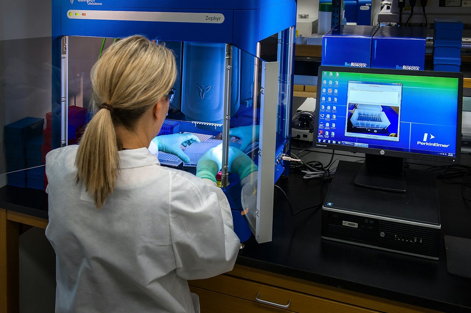 woman in white shirt standing in front of computer