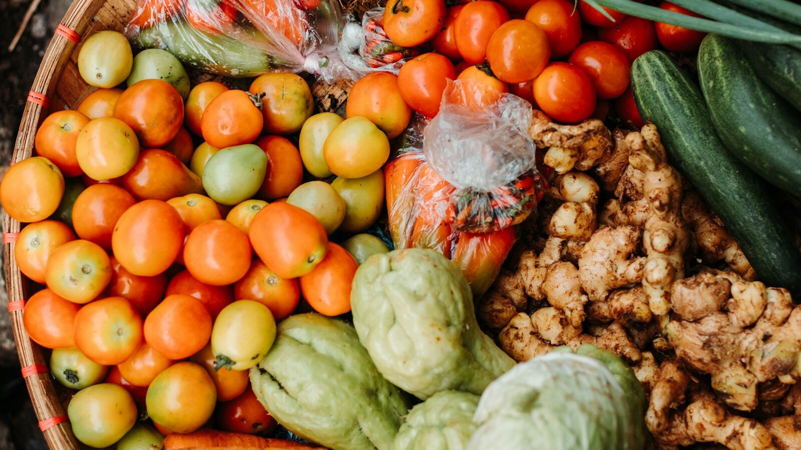 red and orange tomatoes near chayote and cucumbers