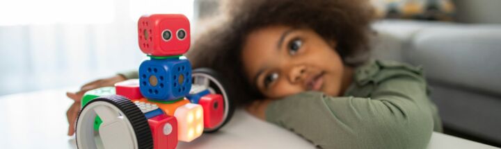 boy lying on bed playing with red and blue toy truck