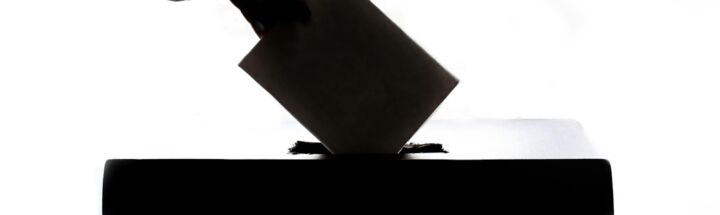 a person is casting a vote into a box