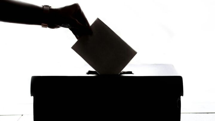 a person is casting a vote into a box