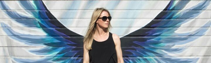 woman taking photo near wings painted wall