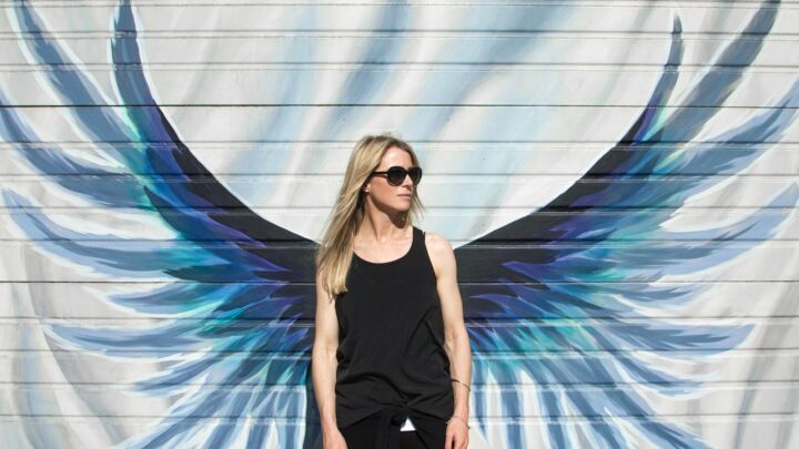 woman taking photo near wings painted wall
