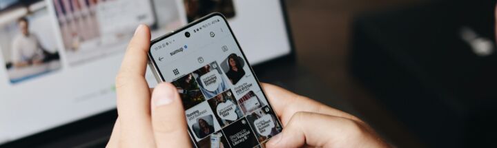 A person holding a cell phone in front of a laptop