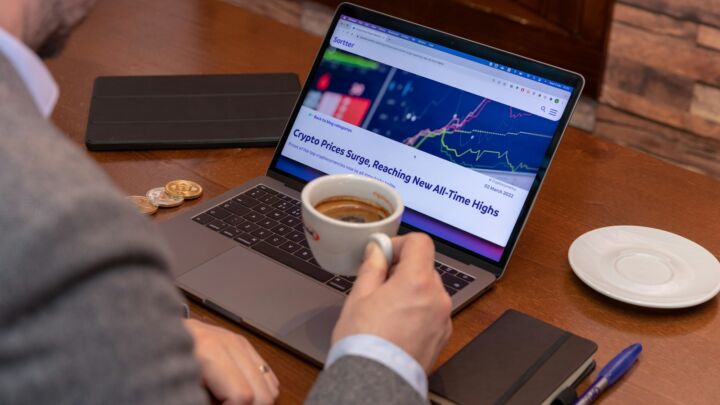 a man sitting at a table with a laptop and a cup of coffee
