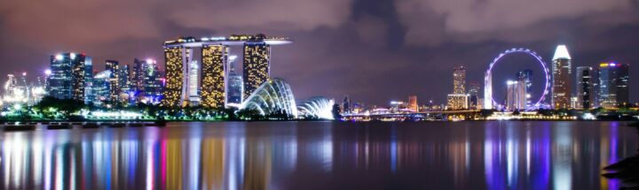 A view of a city at night with a ferris wheel in the distance