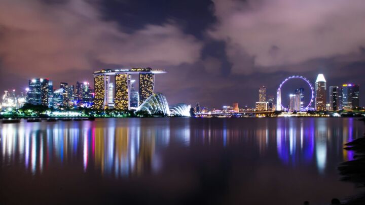 A view of a city at night with a ferris wheel in the distance