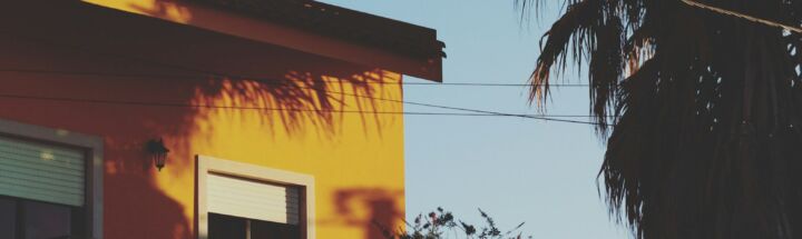 yellow concrete house beside tree