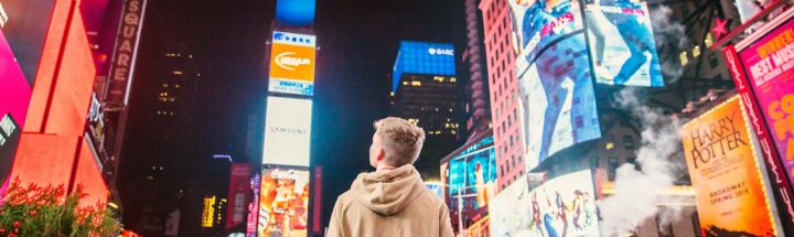 man standing on road infront of high-rise buildi