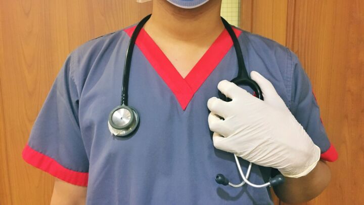 woman in blue scrub suit wearing white mask