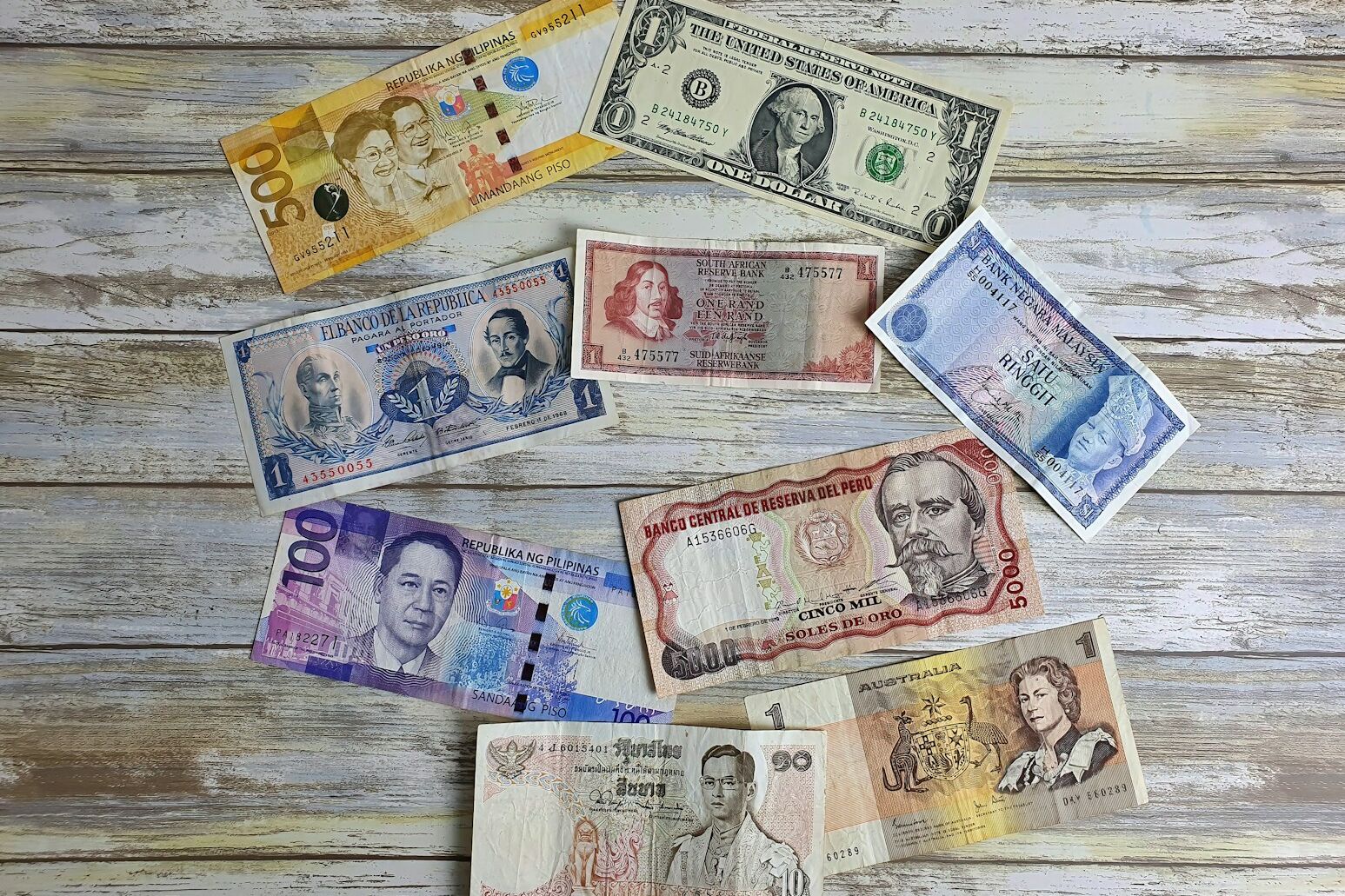a bunch of different currency sitting on top of a wooden table