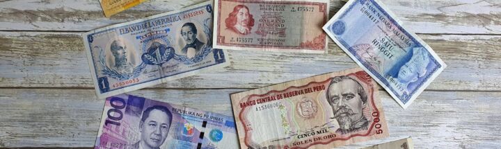 a bunch of different currency sitting on top of a wooden table