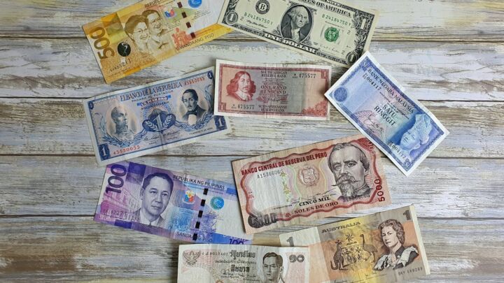 a bunch of different currency sitting on top of a wooden table