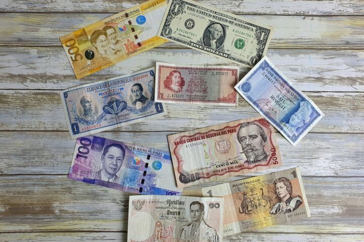 a bunch of different currency sitting on top of a wooden table