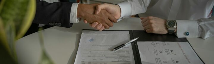 two people shaking hands over a piece of paper