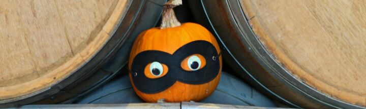 A small pumpkin wearing a black mask with eyes.