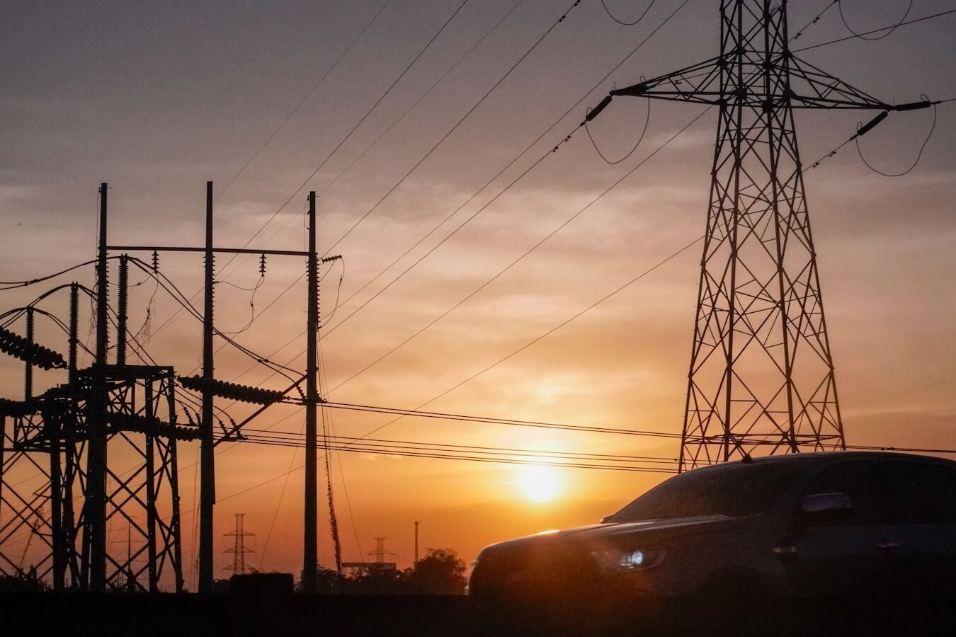 a car is parked in front of power lines at sunset