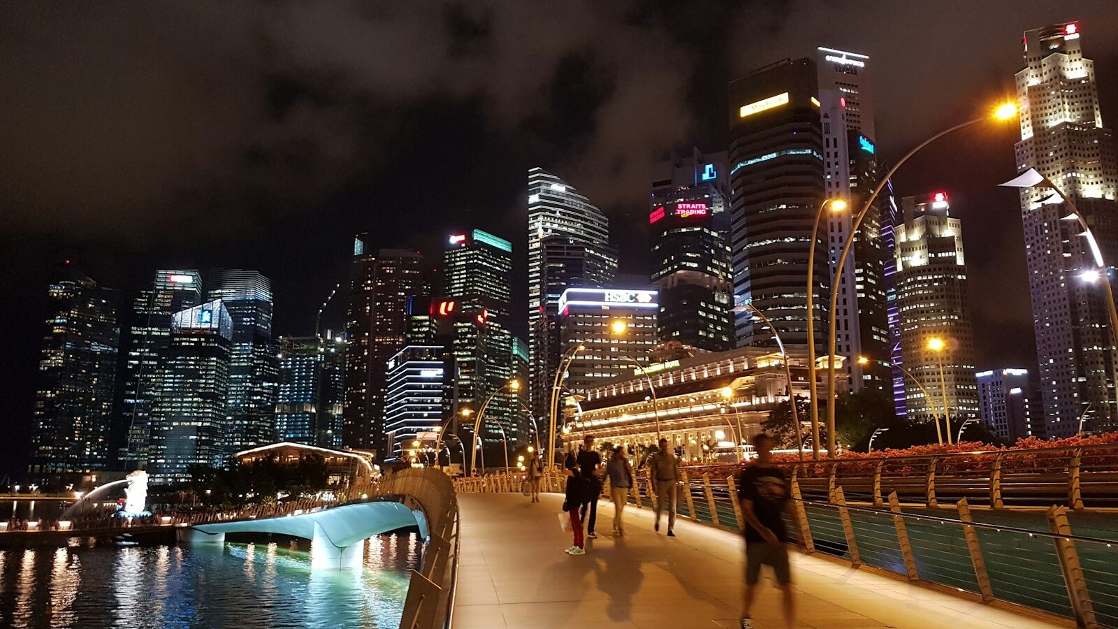 people walking on bridge over body of water during nighttime