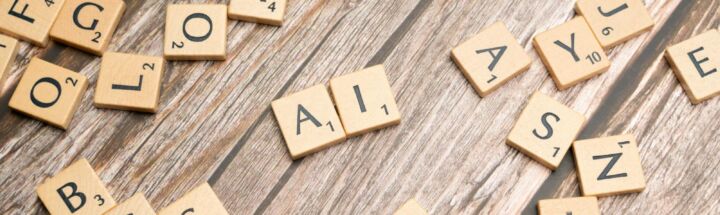 Wooden letter tiles scattered on a textured surface, spelling 'AI'.