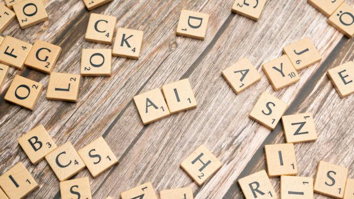 Wooden letter tiles scattered on a textured surface, spelling 'AI'.