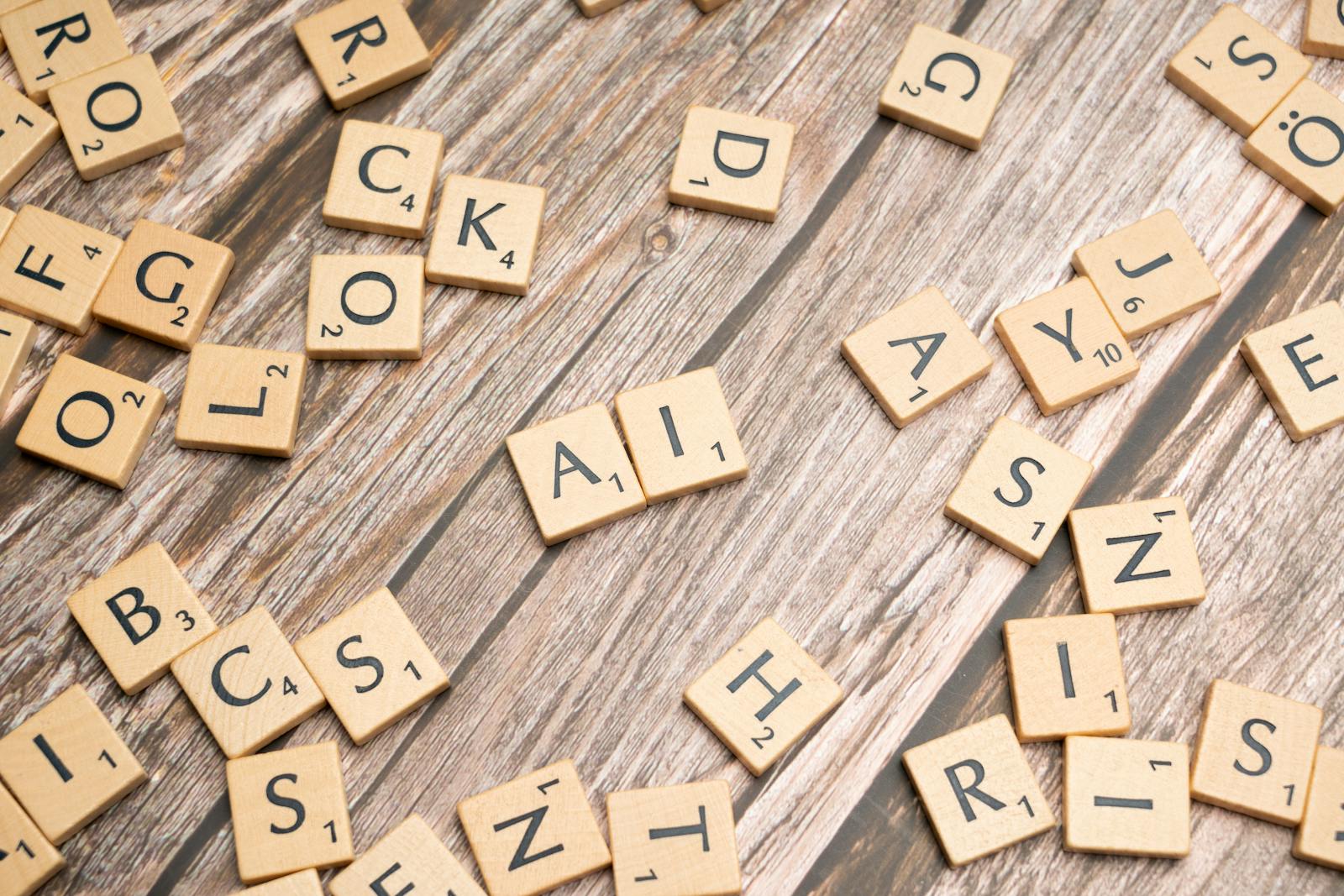 Wooden letter tiles scattered on a textured surface, spelling 'AI'.
