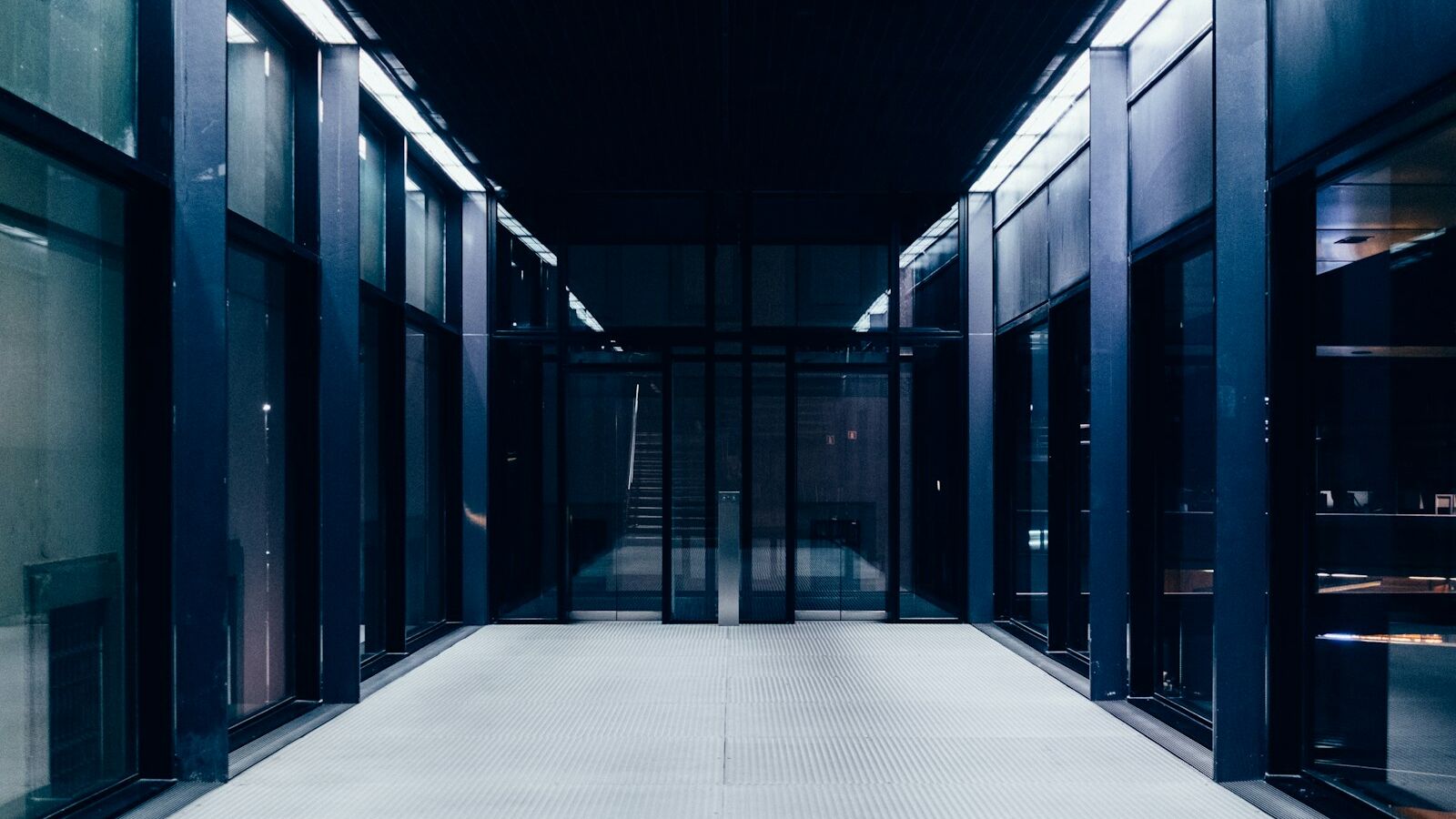 a long hallway with glass doors leading to another room