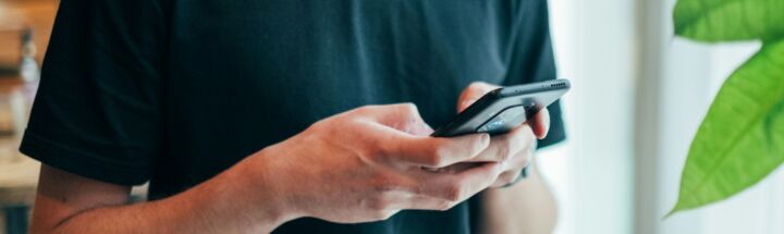 man in black crew-neck top using smartphone