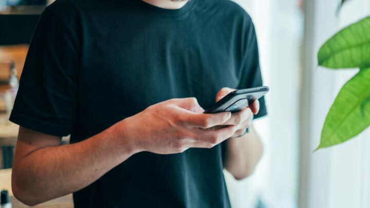 man in black crew-neck top using smartphone