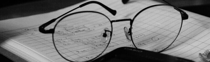 A computer desk with a keyboard, mouse and glasses on it