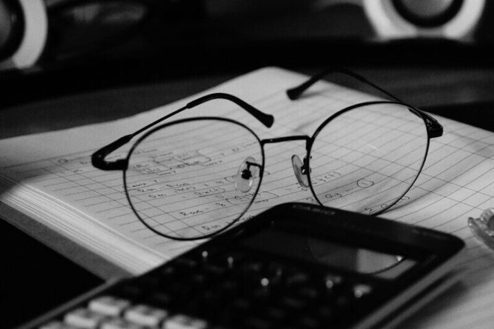 A computer desk with a keyboard, mouse and glasses on it