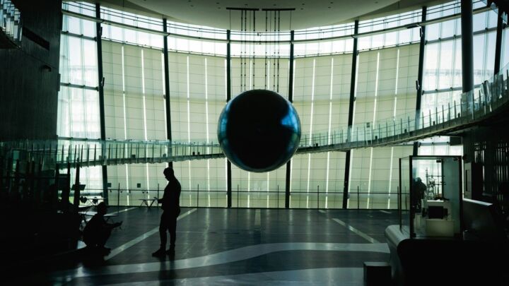 man in black jacket walking on gray floor